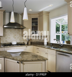 Granite counters in kitchen with triangle work area, tile back splash with pendant lighting, window greenhouse Stock Photo