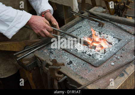 Blacksmith at work heating up the iron in the fire Stock Photo