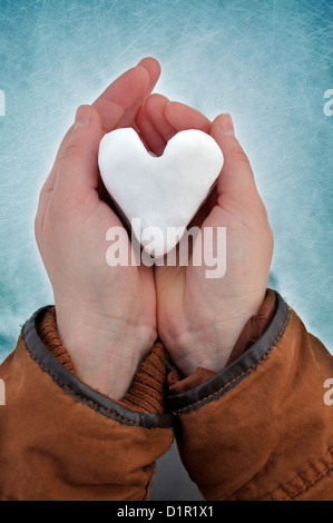 Young woman holding heart shaped snowball Stock Photo