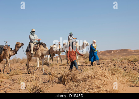 Morocco, M'Hamid, Erg Chigaga. Sahara desert. Camel-driver, camel caravan and tourists making seven day tour through the desert. Stock Photo
