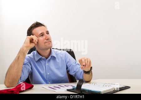 Thinking young entrepreneur at office looking up and holding his hand at his temple. Stock Photo