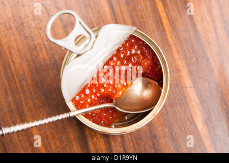red caviar in bank with spoon on wood background Stock Photo