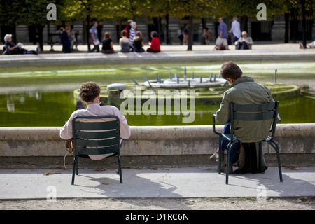 Two young men enjoy the Paris sunshine and sit reading in the open air Stock Photo