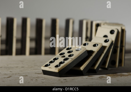 Rows of lined up old ivory and ebony bronze pinned standing domino blocks pieces on white tan Travertine marble Stock Photo