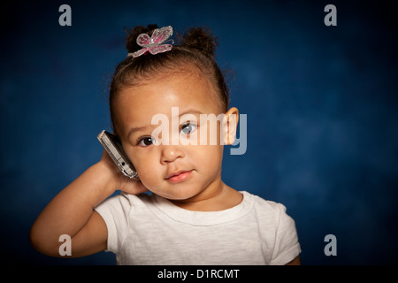 Studio portrait of cute mixed race toddler girl with a mobile phone Stock Photo