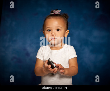 Studio portrait of cute mixed race toddler girl with a mobile phone Stock Photo