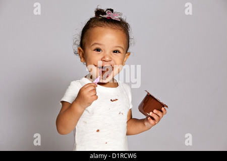 Cute little girl, toddler, making a mess eating a chocolate desert. Stock Photo