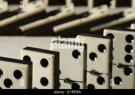 Rows of lined up old ivory and ebony bronze pinned standing domino blocks pieces on white tan Travertine marble Stock Photo