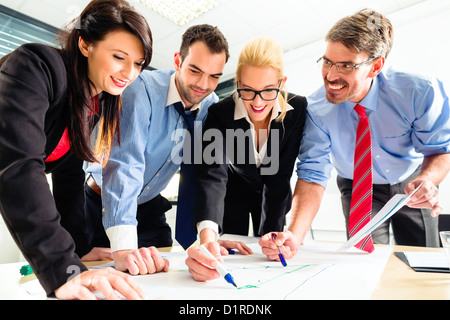 Four professionals in office in business attire having strategy meeting to determine the future of company Stock Photo