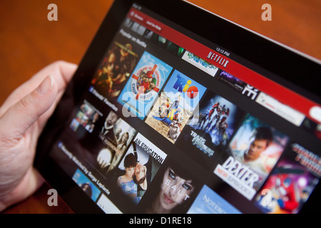 A woman uses the Netflix app on an iPad 4. Netflix, Inc. is an American provider of on-demand Internet streaming media. Stock Photo