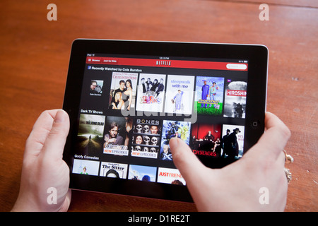 A woman uses the Netflix app on an iPad 4. Netflix, Inc. is an American provider of on-demand Internet streaming media. Stock Photo