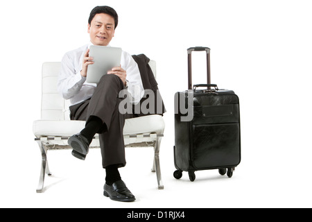 Businessman on a trip playing digital tablet at leisure Stock Photo