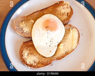 A fried egg on two slices of buttered toasted Rye Bread ready to eat Stock Photo