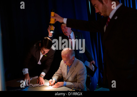 US Vice President Joe Biden signs autographs as staff hold flashlights so the Vice President can see backstage at West York Area High School September 2, 2012 in York, PA. Stock Photo