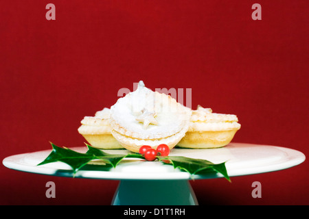 Freshly made mince pies on a cake stand against a red background. Stock Photo