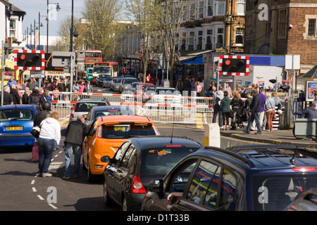 Level crossing with barriers down and queue of waiting traffic in Paignton, Devon Stock Photo