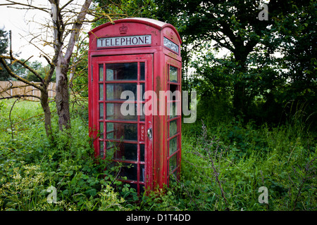 An old Red Telephone Box stands forlorn near a roadside in Worcestershire as it steadily loses it's battle with the environment Stock Photo