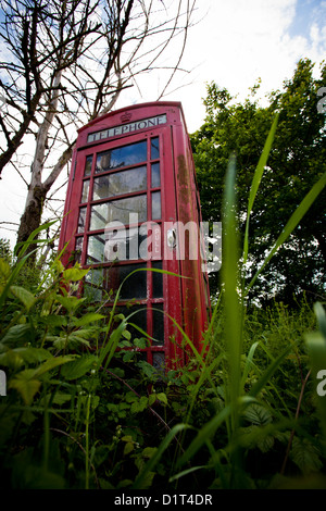 An old Red Telephone Box stands forlorn near a roadside in Worcestershire as it steadily loses it's battle with the environment Stock Photo