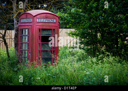 An old Red Telephone Box stands forlorn near a roadside in Worcestershire as it steadily loses it's battle with the environment Stock Photo