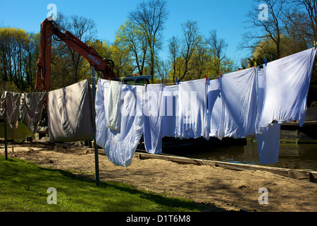 Laundry dries on a clothesline, with an excavator on a waterside construction site in the background, on Dr.-Julius-Leber-Straße in Lübeck, Germany. Stock Photo