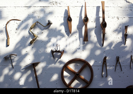 Old, rusting, farm tools hanging on a wall Stock Photo