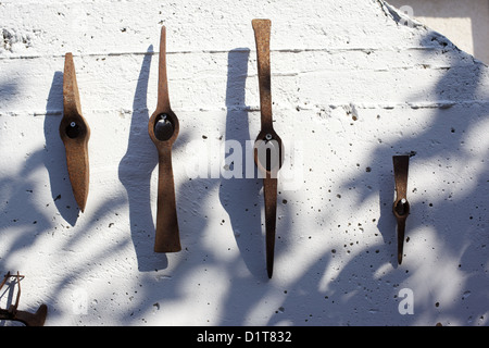 Old, rusting, farm tools hanging on a wall Stock Photo