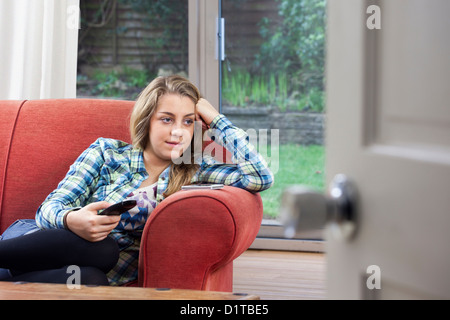 Teenage girl relaxing watching tv, sitting on a sofa. Stock Photo