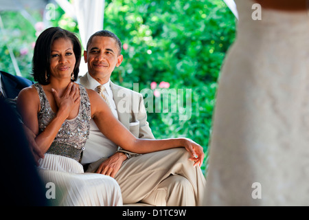 US President Barack Obama smiles as his wife First Lady Michelle reacts as she watches Laura Jarrett and Tony Balkissoon take their vows during their wedding June 18, 2012 in Chicago, IL. Stock Photo