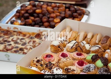 Three boxes of various French desserts sit on a white table at a garden party. Stock Photo