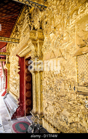 LUANG PRABANG, Laos - The ornate gold decorations on the outside walls at Wat Mai Suwannaphumaham.  Wat Mai, as it is often known, is a Buddhist temple in Luang Prabang, Laos, located near the Royal Palace Museum. It was built in the 18th century and is one of the most richly decorated Wats in Luang Prabang. Stock Photo