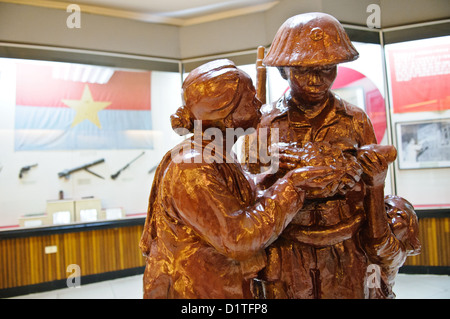 HANOI, Vietnam — A statue in the foreground, with a revolutionary flag and guns in the exhibit case in the background at left. The Museum of the Vietnamese Revolution in the Tong Dan area of Hanoi, not far from Hoan Kiem Lake, was established in 1959 and is devoted to the history of the socialist revolutionary movement in Vietnam. Stock Photo