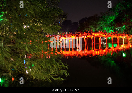 HANOI, Vietnam — Many tourists visit the The Huc Bridge (Morning Sunlight Bridge) at night. The red-painted, wooden bridge joins the northern shore of the lake with Jade Island and the Temple of the Jade Mountain (Ngoc Son Temple). Stock Photo