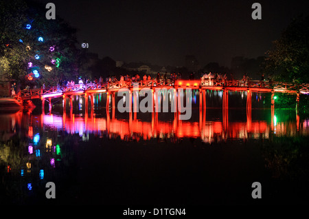 HANOI, Vietnam — View of The Huc Bridge (Morning Sunlight Bridge) from the northern shore of Hoan Kiem Lake at night. The red-painted, wooden bridge joins the northern shore of the lake with Jade Island and the Temple of the Jade Mountain (Ngoc Son Temple). Stock Photo