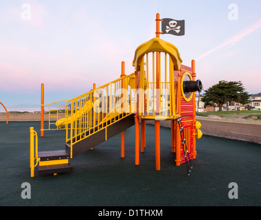 Childrens climbing frame at dawn in shape of a pirate ship with flag Stock Photo