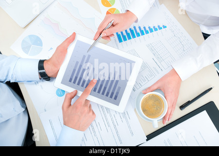 Business people discussing and analyzing market data information on a modern digital tablet computer. Top view photoshoot. Stock Photo