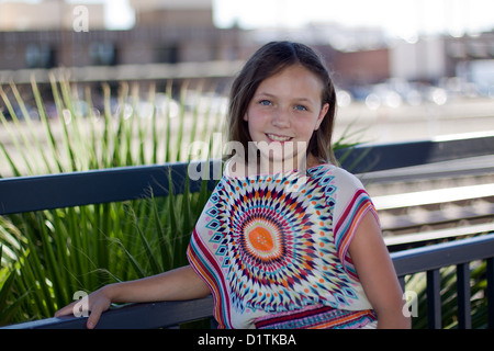 A young pre teen Caucasian girl modeling 1960s style tie dyed clothes. She has blue eyes and  a playful warm smile. She is weari Stock Photo