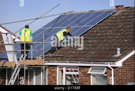 WORKMEN FITTING SOLAR PANELS TO A DOMESTIC HOUSE ROOF ENERGY BILLS COSTS PRICES SUN POWER ELECTRICITY NATIONAL GRID HEATING UK Stock Photo