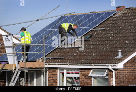 WORKMEN FITTING SOLAR PANELS TO A DOMESTIC HOUSE ROOF RE ENERGY BILLS COSTS PRICES SUN POWER ELECTRICITY NATIONAL GRID HEAT UK Stock Photo