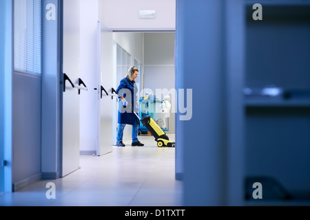 Woman working, professional maid cleaning and washing floor with machinery in industrial building Stock Photo