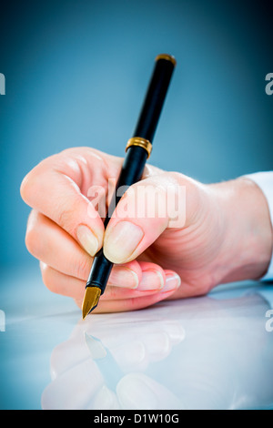 Woman's hand with a pen on a blue background Stock Photo