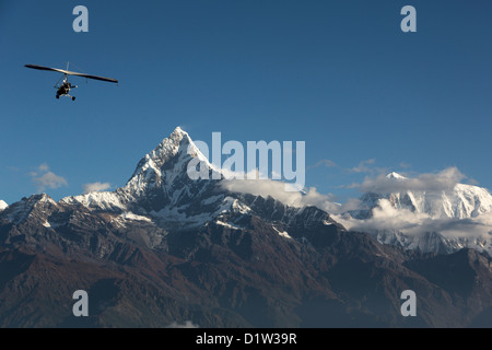 Microlight flying near the Machapuchare (aka fishtail mountain) in the Annapurna Sanctuary, Nepal Stock Photo