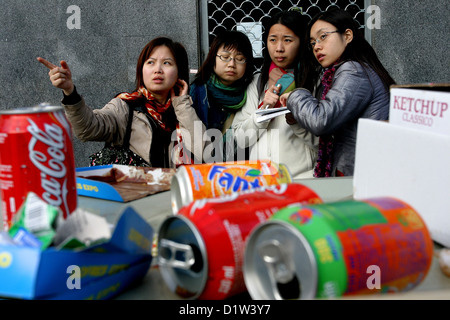 four Asian girls, in front of empty cans Seville Spain Stock Photo