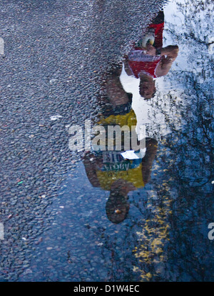 Two 2008 London marathon runners reflected in a roadside puddle London England Europe Stock Photo