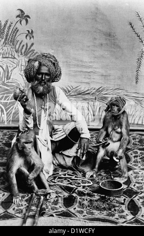 India - Fakir with monkeys Indian Fakir, full-length portrait, seated on cloth with two monkeys. Circa 1900 Stock Photo