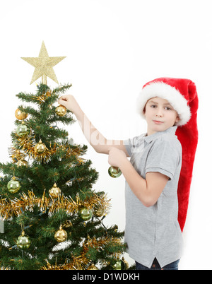Boy with santa hat decorates the Christmas tree on white background Stock Photo