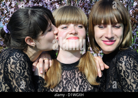 three cheerful showgirls relaxing outdoors near the blooming tree Stock Photo
