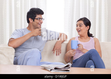 Cheerful young couple having coffee at home Stock Photo