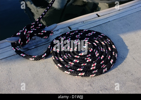 A black, pink and white boat mooring line coiled on the finger birth at the Royal Phuket Marina Thailand Stock Photo