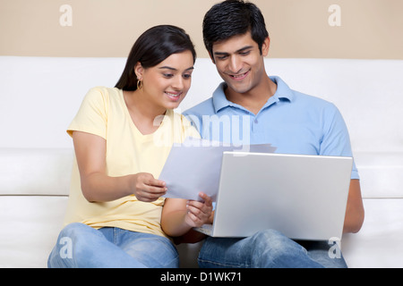 Young Indian couple reading document while using laptop Stock Photo