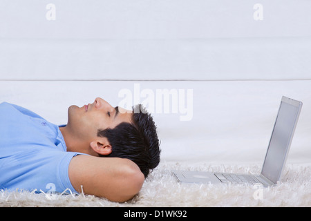 Man lying down in front of laptop Stock Photo